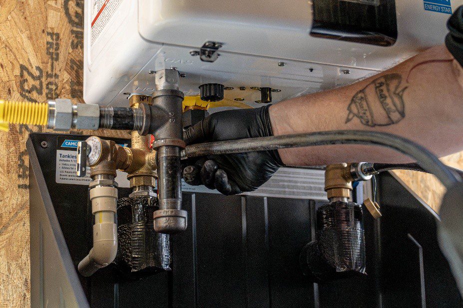 Licensed plumber performing gas line maintenance and securing fittings on a tankless water heater during a residential service call in Lewisville, TX