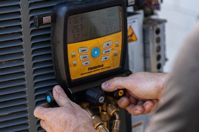 HVAC technician performing air handler inspection and maintenance on a residential Trane system during a service call in Lewisville, TX.