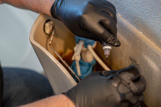Residential plumber fixing a toilet tank mechanism during a home plumbing repair service in Lewisville, TX