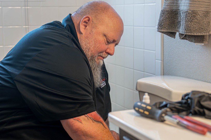 Plumbing technician fixing a residential toilet during a bathroom repair service in Lewisville, TX.